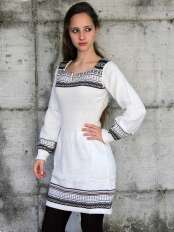 Woman wearing a short white alpaca dress with black, beige and grey jacquard pattern on the hem and sleeves, model Giuditta.