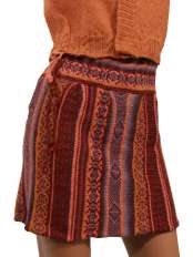 Close-up of a short red winter skirt in alpaca knit, with geometric pattern and waist ties, model Giuditta.