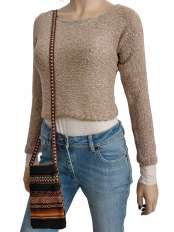 On a white background, woman wearing a beige cropped jumper in baby alpaca and Pima cotton, model Fiona, jeans and a Peruvian ethnic phone pouch.